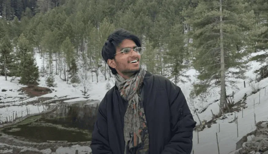 Portrait in a scarf and dark coat, laughing, in a stand of pines under fresh snow